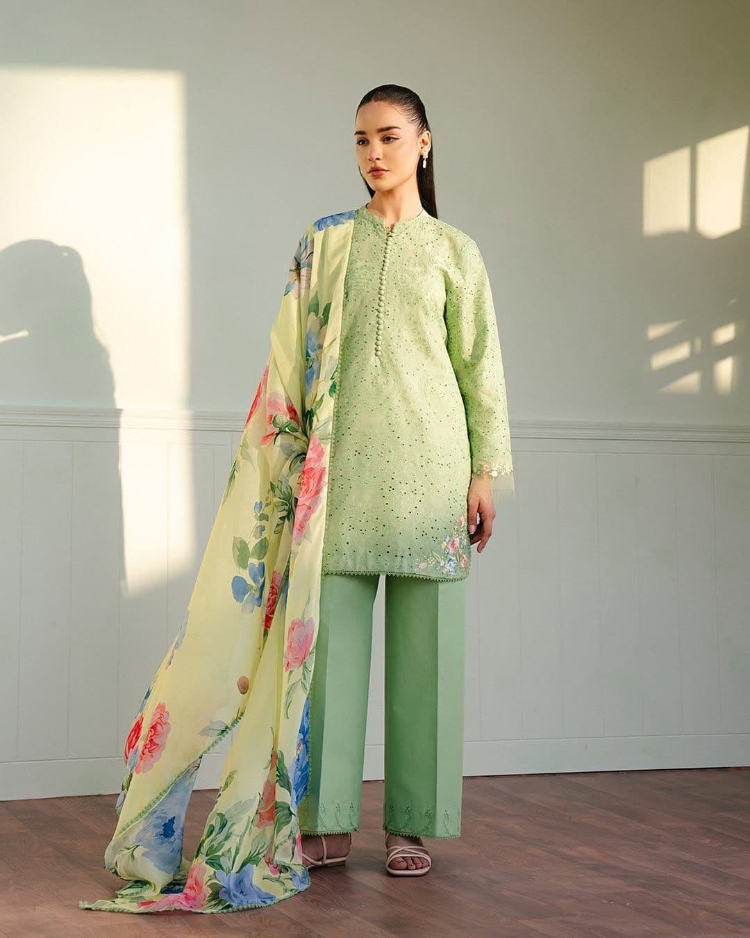 Woman in a light green embroidered tunic and trousers with a yellow floral dupatta.